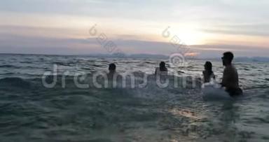 一群在日落时分在海中嬉戏的朋友，一群快乐的年轻人在暑假一起在沙滩上游泳
